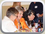 Sue Burdick, eating, two women wives of classmates, and back Mark Scott and wife Amy.